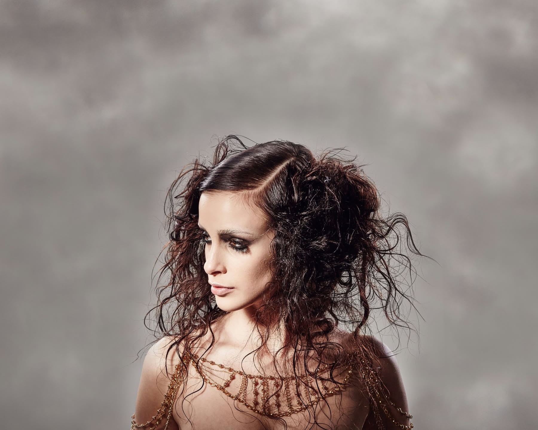 Donna con capelli corti mossi castani, riga laterale, movimento ondulato naturale, cuoio capelluto visibile, illuminazione naturale