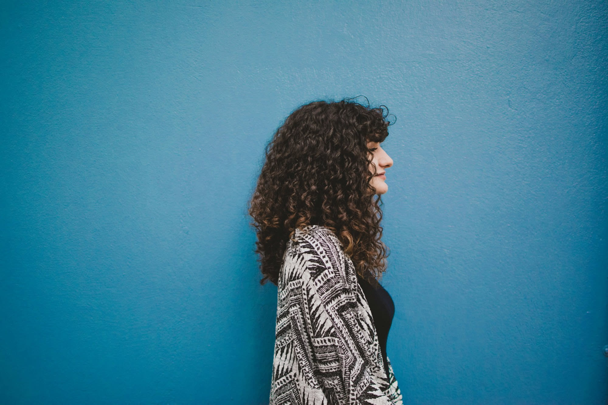 Donna con capelli ricci castani e frangia morbida ondulata che incornicia il viso, con texture naturale ben definita